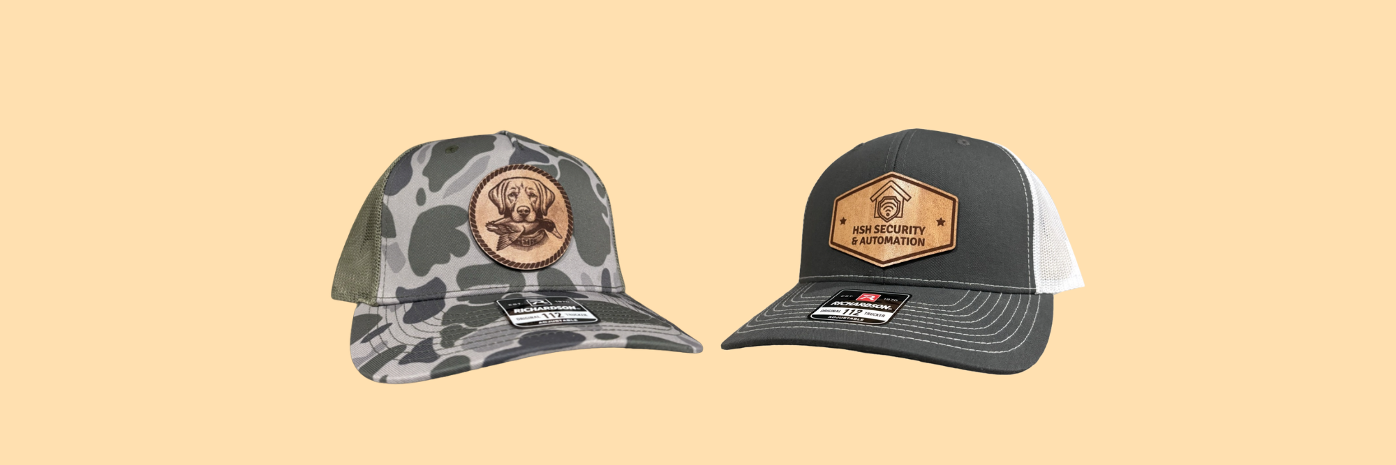 Two trucker-style caps shown side by side on a solid pale peach background. The left cap has a gray and black camouflage front panel with a circular brown leather patch.